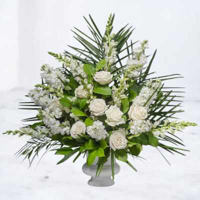 Tall white rose and snapdragon arrangement in a white pedestal vase