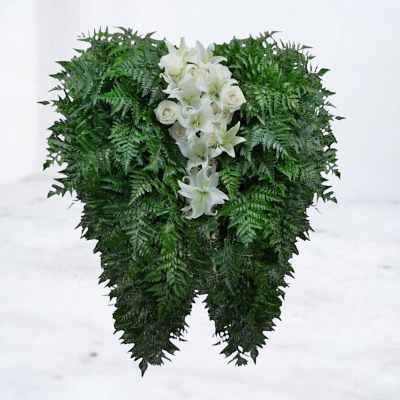 White lilies and roses arranged in a dense green standing spray