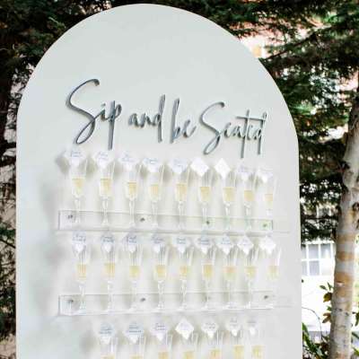 White seating chart board with rows of champagne flutes