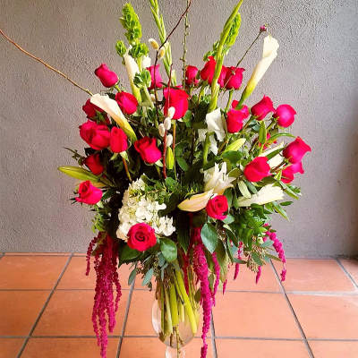 Tall bouquet of red roses, white calla lilies, and lilies in a glass vase