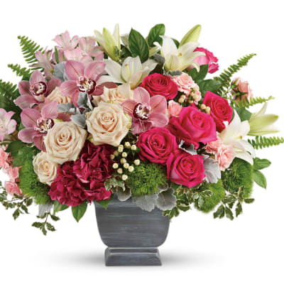 Mixed bouquet of roses, lilies, and orchids in a gray vase