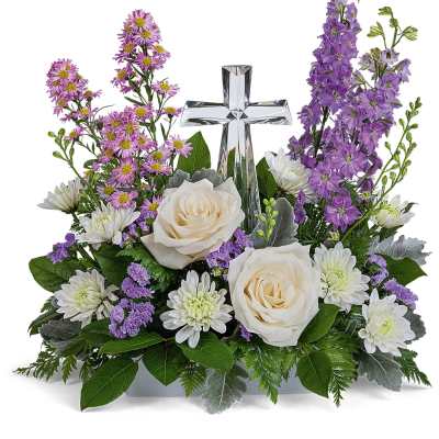 White roses and purple flowers arranged around a glass cross