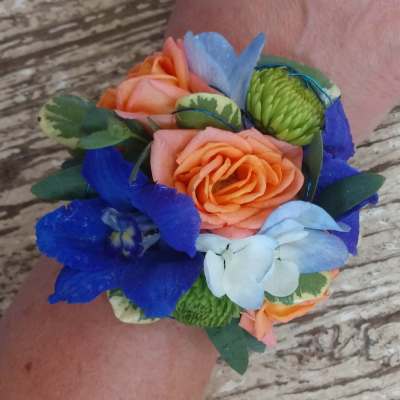 Wrist corsage with orange roses and blue flowers