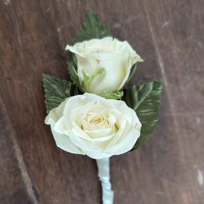 White rose boutonniere with green leaves on a wrapped stem