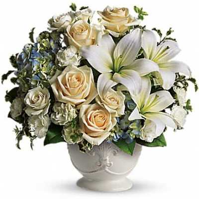 Bouquet of cream roses and white lilies in a white vase