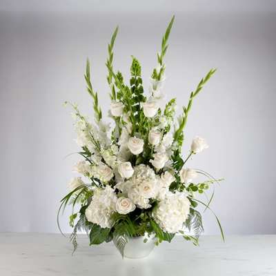 White floral arrangement in a white vase with tall green accents