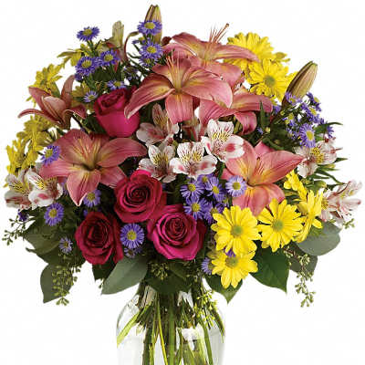 Mixed bouquet of pink lilies, roses, and yellow daisies in a glass vase