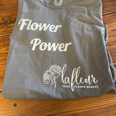 Folded gray T-shirt with white flower-themed text and graphic