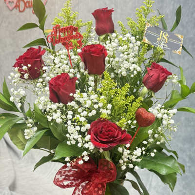 Red roses with baby's breath in a gold vase and red ribbon