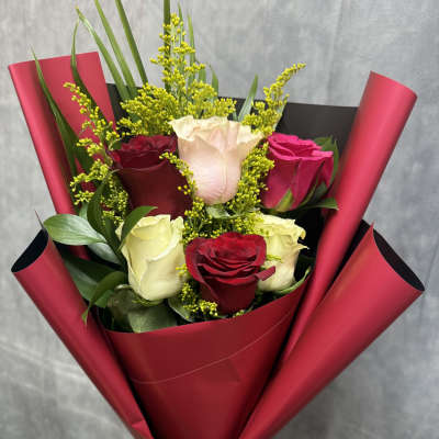 Bouquet of red, white, and pink roses wrapped in burgundy paper