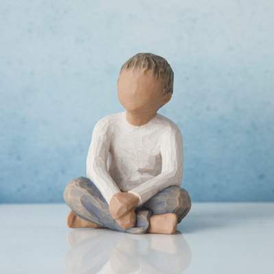 Small faceless seated figurine with a white shirt and blue pants