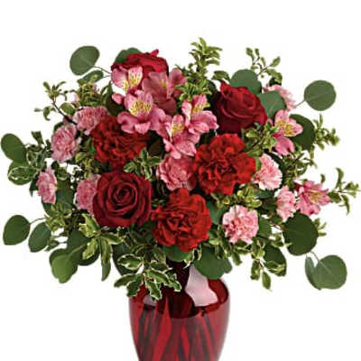 Red roses and pink alstroemeria in a red glass vase