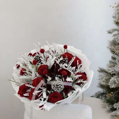 Bouquet of red roses with frosted white accents and pinecones