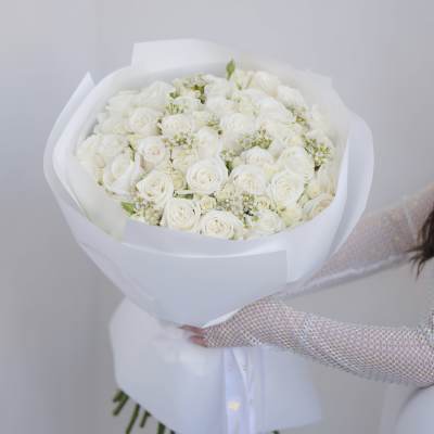 Large bouquet of white roses wrapped in white paper