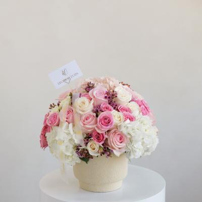 Pink and white rose bouquet in a cream vase