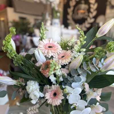 Mixed bouquet with pale pink gerbera daisies and white orchids in a glass vase