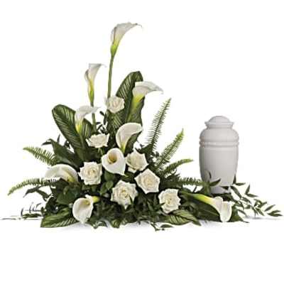 White calla lilies and roses arranged beside a white urn
