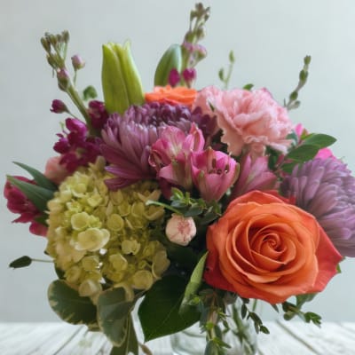 Mixed bouquet with roses, carnations, hydrangea, and lilies in a glass vase