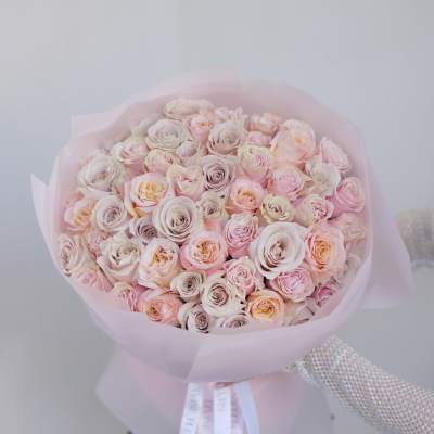 Bouquet of pale pink and cream roses wrapped in pink paper
