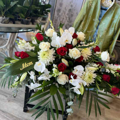 Red and white rose arrangement with white orchids and a gold "Mom" pick