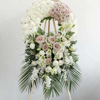 Large white and blush floral wreath on a wooden stand