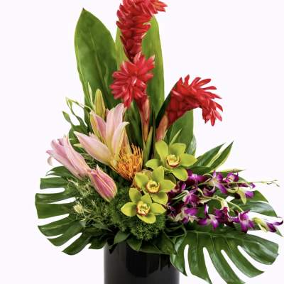 Tropical flower arrangement in a black vase with red, pink, green, and purple blooms