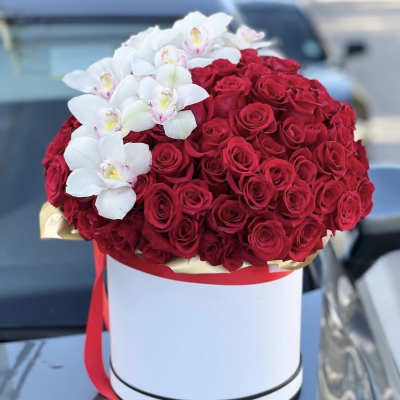 Red roses and white orchids arranged in a white hat box