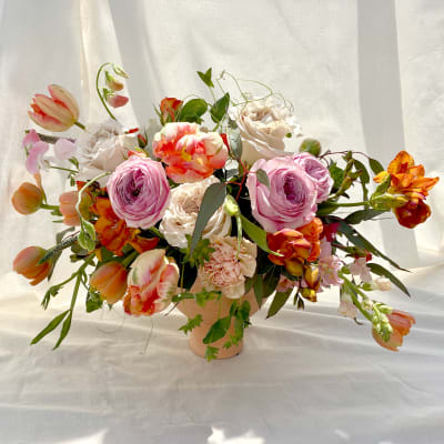 Mixed bouquet of pink, white, and orange flowers in a peach vase