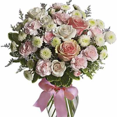 Pink and white rose bouquet in a glass vase with a pink ribbon
