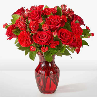 Red roses and carnations in a red glass vase