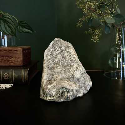 Crystal geode on a dark surface with glass vases and greenery