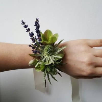 Wrist corsage with green textured blooms and small purple sprigs on a cream ribbon