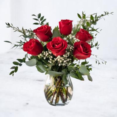 Arrangement of red roses with white filler flowers in a clear glass vase