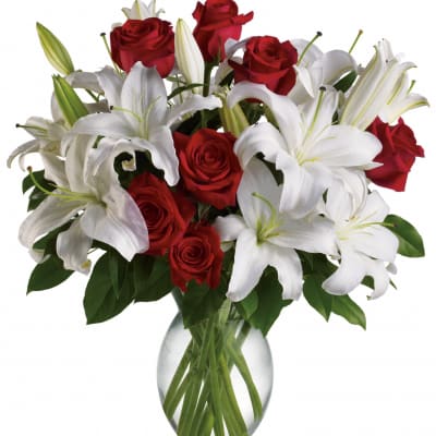 Red roses and white lilies arranged in a clear glass vase