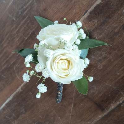 White rose boutonniere with baby's breath and green leaves