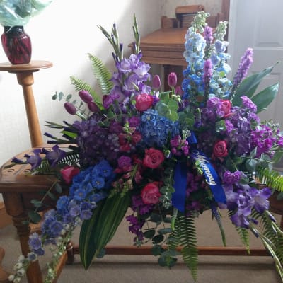 Large bouquet of purple, blue, and pink flowers with a blue ribbon