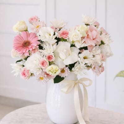 Pink and white mixed bouquet in a white vase with a ribbon
