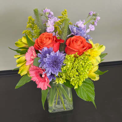Mixed bouquet in a clear glass vase with roses, daisies, and alstroemeria