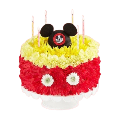 Round floral cake in red and yellow with candles and a black mouse-ear topper on a white stand