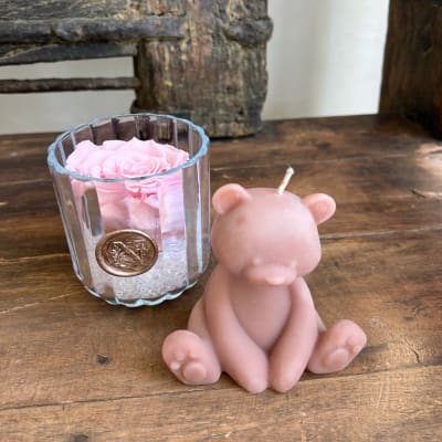 Pink rose in a glass votive beside a pink bear-shaped candle