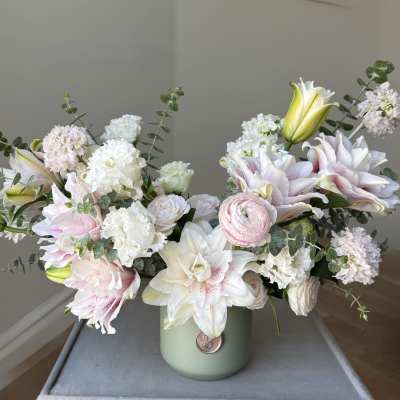 Pastel bouquet of lilies, carnations, and ranunculus in a green vase
