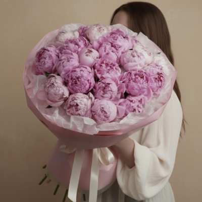 Large bouquet of pink peonies wrapped in pink paper with a white ribbon
