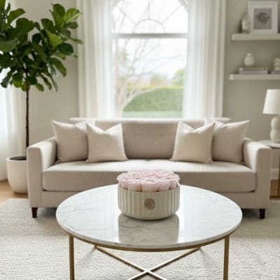 Round box of pale pink roses on a coffee table in a living room