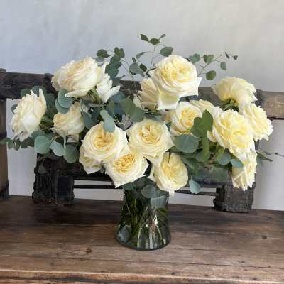 Cream roses arranged in a glass vase with eucalyptus