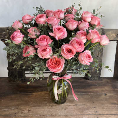 Pink roses arranged in a glass vase with a ribbon