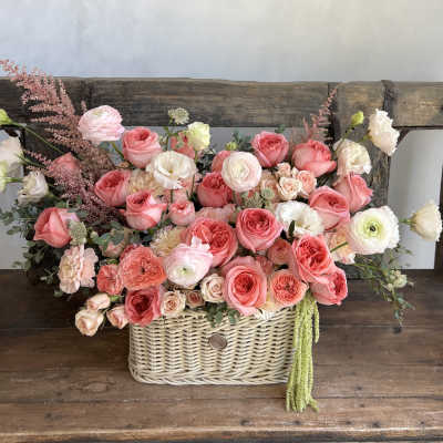Basket arrangement of pink and white roses with mixed blooms