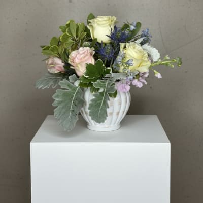 Mixed bouquet in a white vase with pale roses and blue thistle