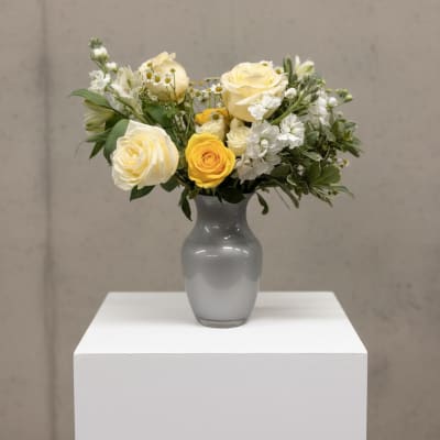 Yellow and white roses arranged in a gray vase