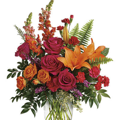 Bright mixed bouquet of roses, lilies, and carnations in a clear glass vase
