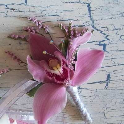 Pink orchid boutonniere with ribbon and small decorative accents